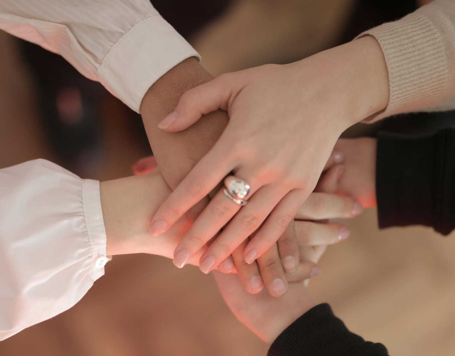 Diverse group of hands joined together in a teamwork gesture.